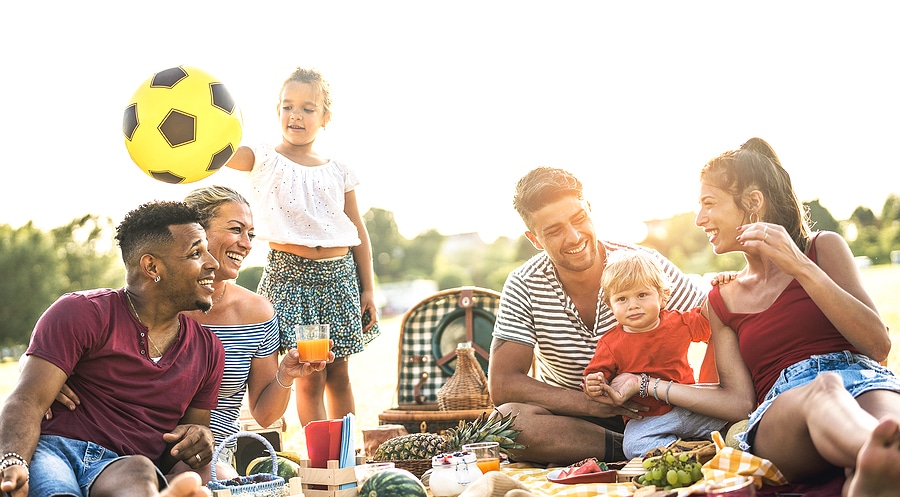 Happy multiracial families having fun together with kids at pic nic barbecue party - Multicultural joy and love concept with mixed race people playing with children at park - Warm contrasted filter